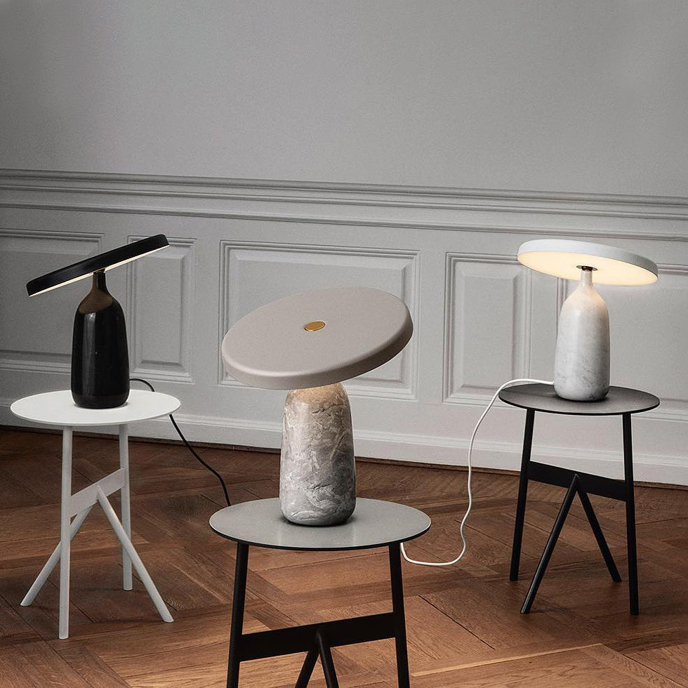 Three Clérachic table lamps in black, grey marble and white finishes grouped on trestle tables, close view of a panelled room.