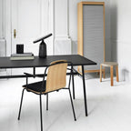 Black Clérachic table lamp on the black desk, photographed closer to show the disc shade above the bottle base.