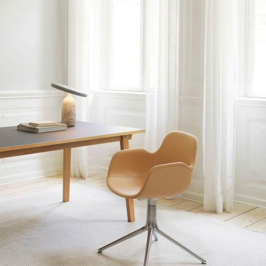 Grey marble Clérachic table lamp on a wooden desk beside stacked books, near a window with a tan chair.