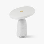 White marble table lamp from Clérachic on a plain background, its flat disc shade tilted to one side on the brass ball joint.
