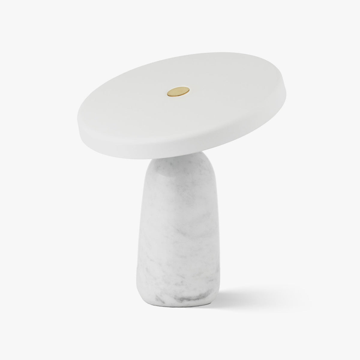 White marble table lamp from Clérachic on a plain background, its flat disc shade tilted to one side on the brass ball joint.