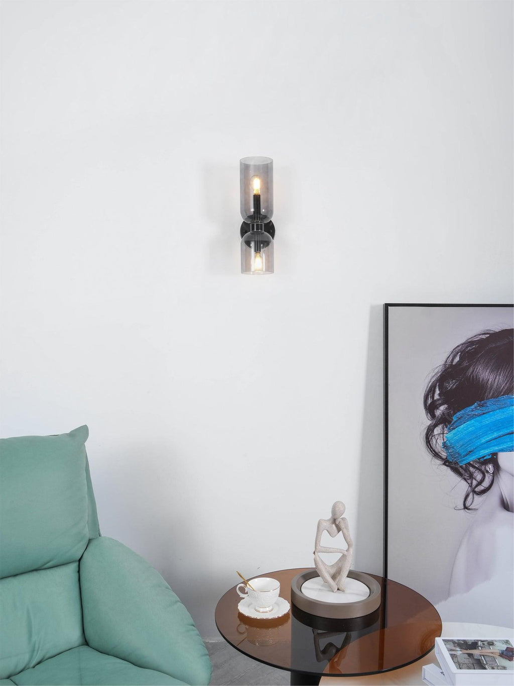 Beside a green cushion and framed art, this matt black Clérachic wall light shows clear glass shades.