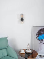 Beside a green cushion and framed art, this matt black Clérachic wall light shows clear glass shades.