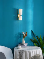 On a teal wall above a flower-topped table, this gold Clérachic sconce's opal shades glow warmly.