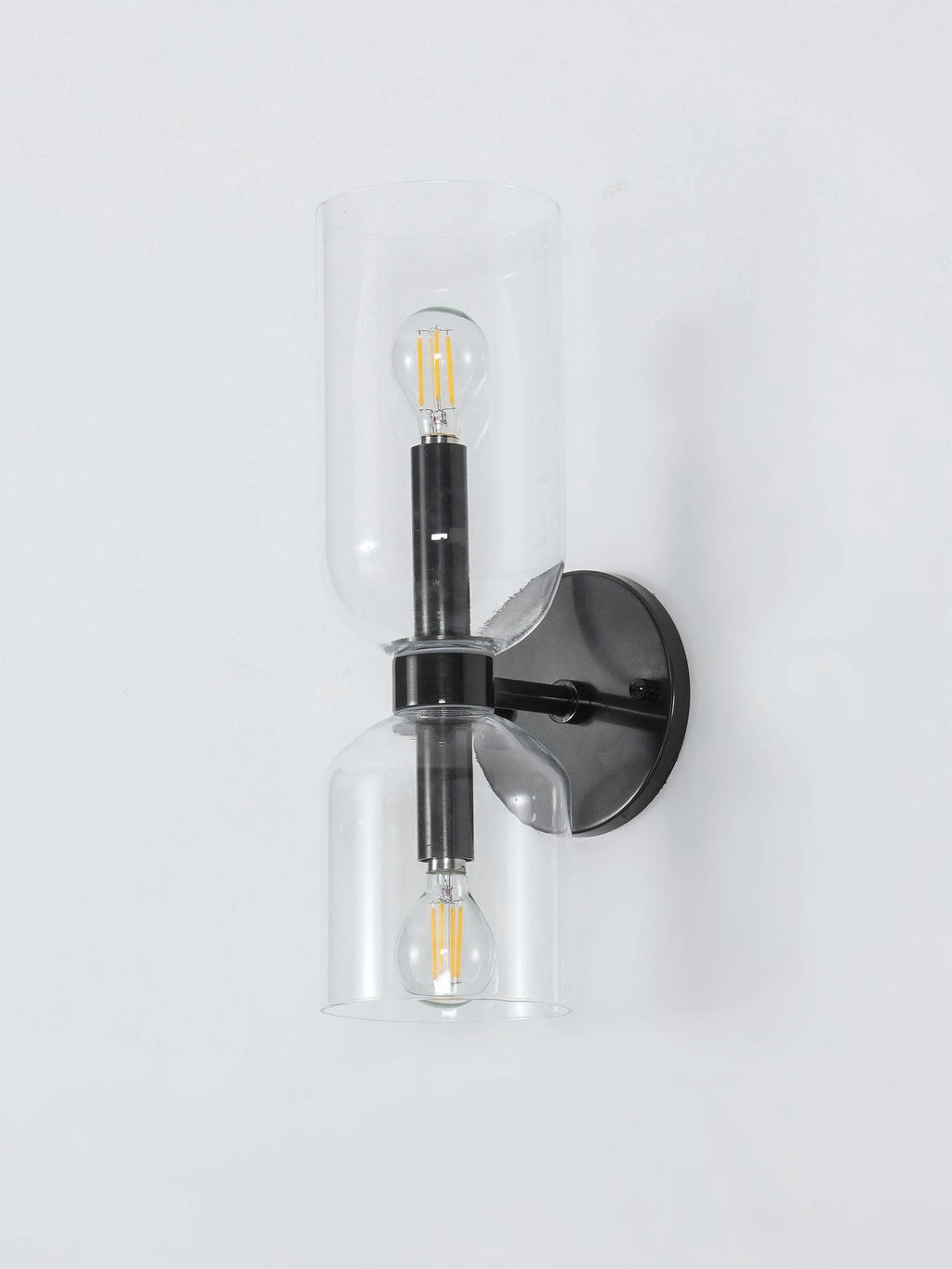 Round backplate and clear glass cylinders define this matt black Clérachic wall light on a white background.