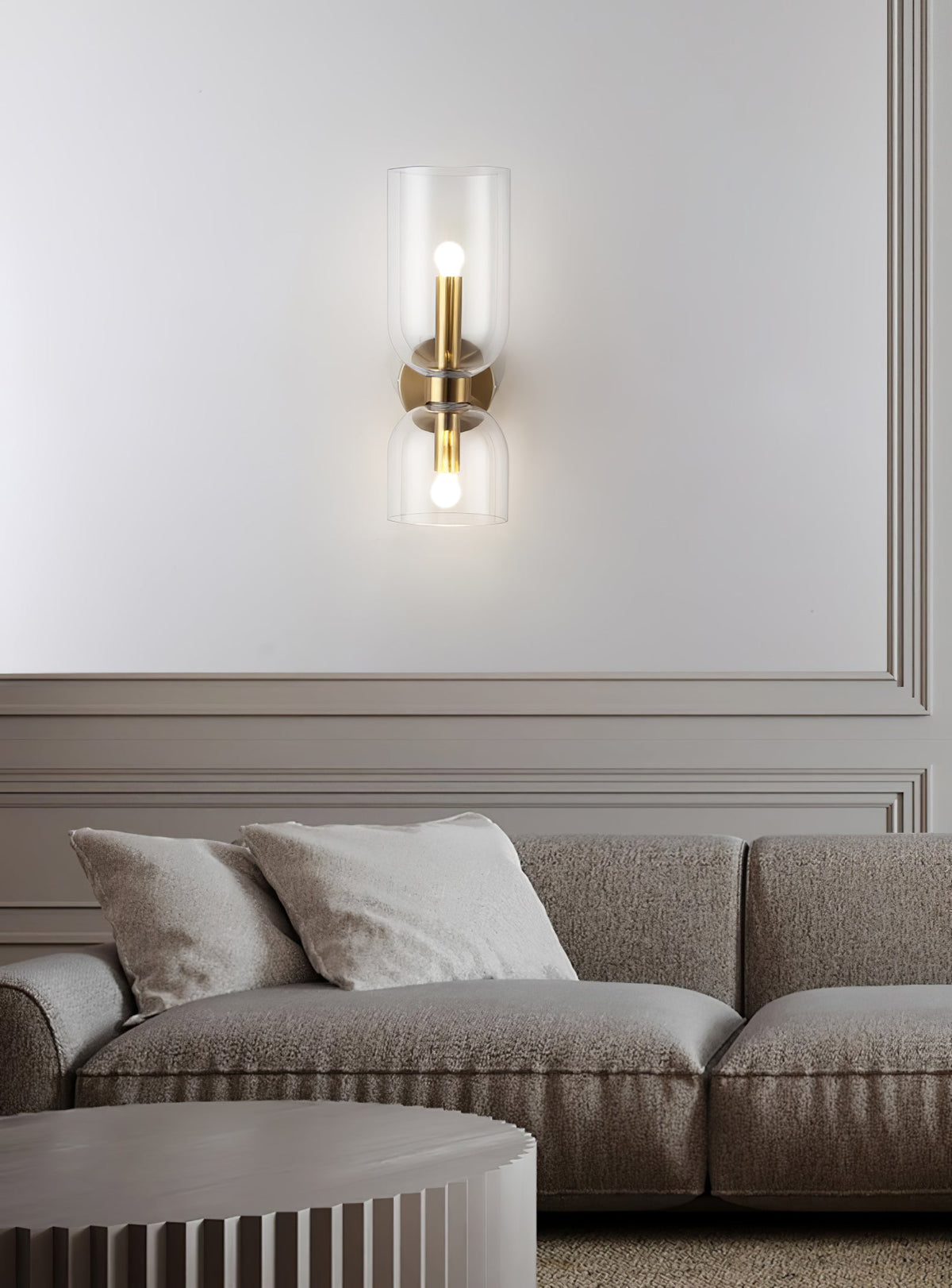 Seen from across a grey sofa, this gold Clérachic sconce lights a panelled living room wall.