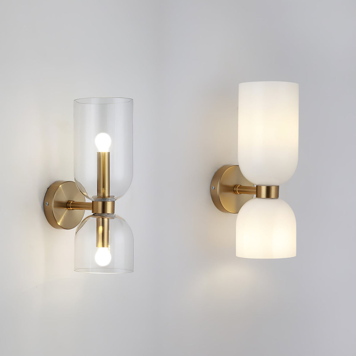 Side by side, two Clérachic wall lights in gold compare clear glass cylinders with opal dome shades.