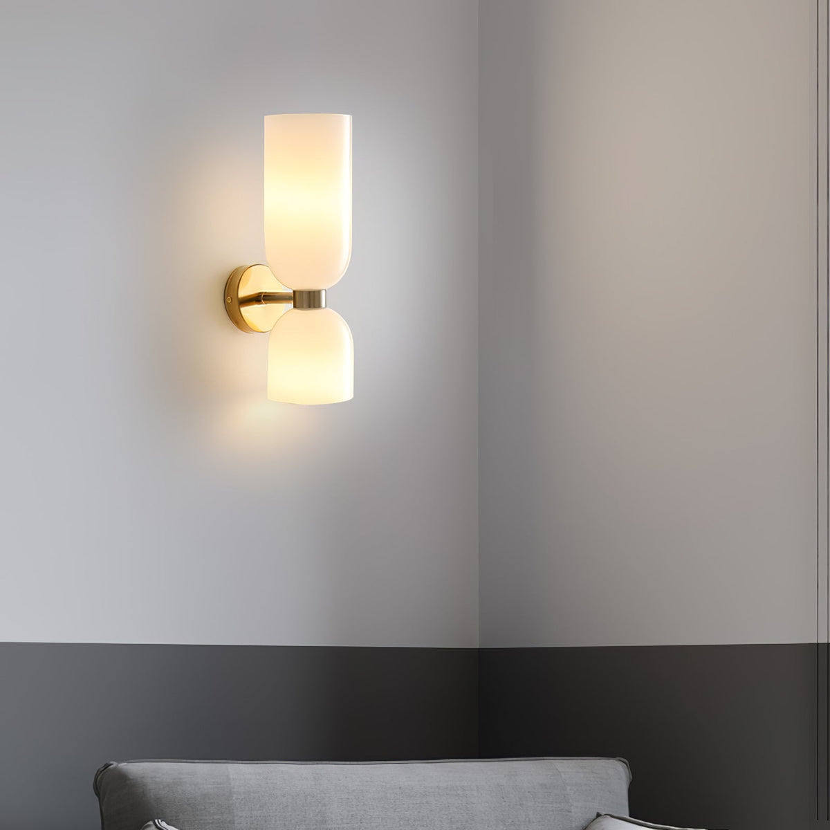 Mounted in the corner of a two-tone grey room, this gold Clérachic wall light sits above a sofa.