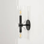 A narrow view shows the cord and clear glass shades of this matt black Clérachic wall light, lit.