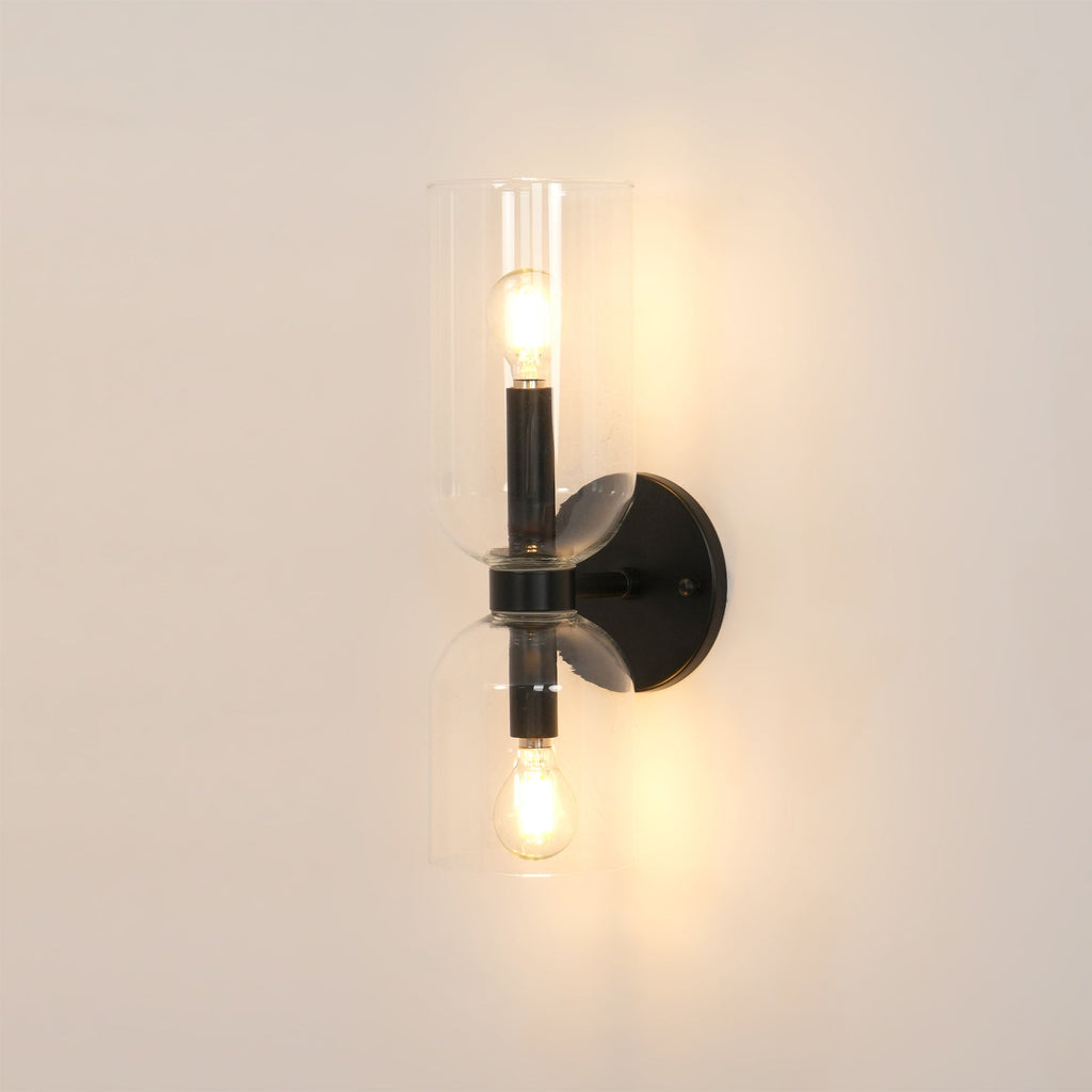 Warm light glows through the clear glass cylinders of this matt black Clérachic sconce.