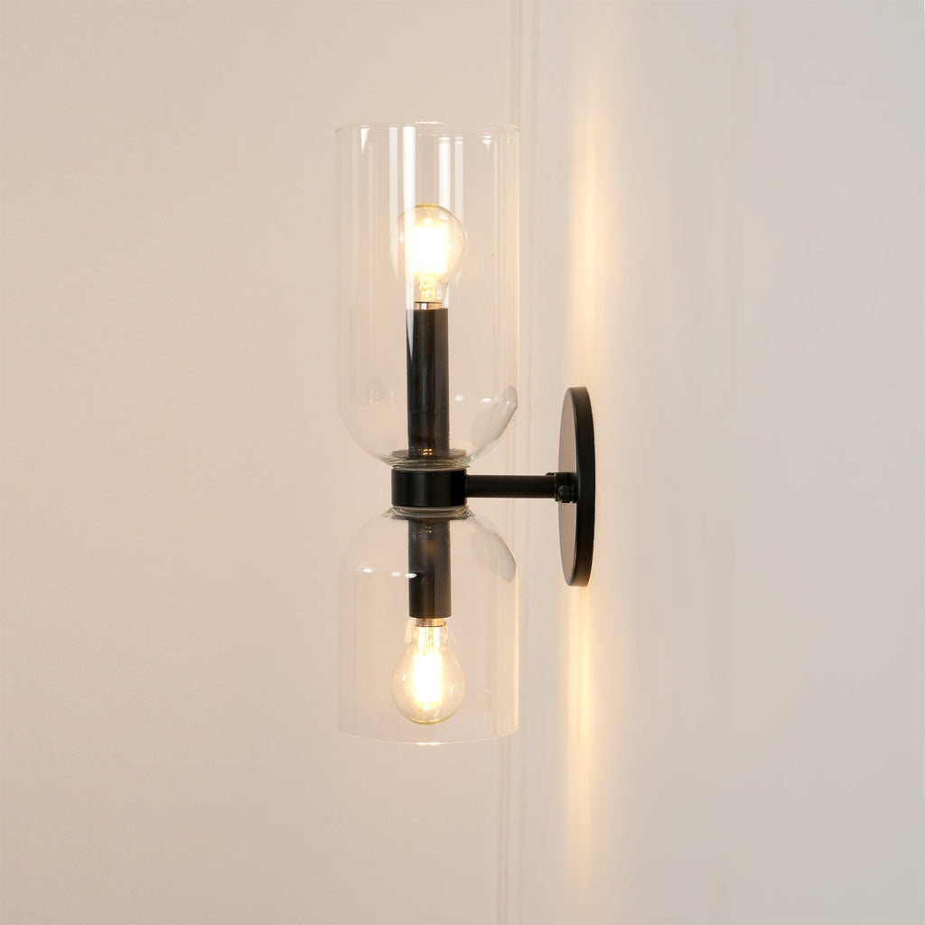 Seen from the side, this matt black Clérachic wall light's clear glass shades glow gently.