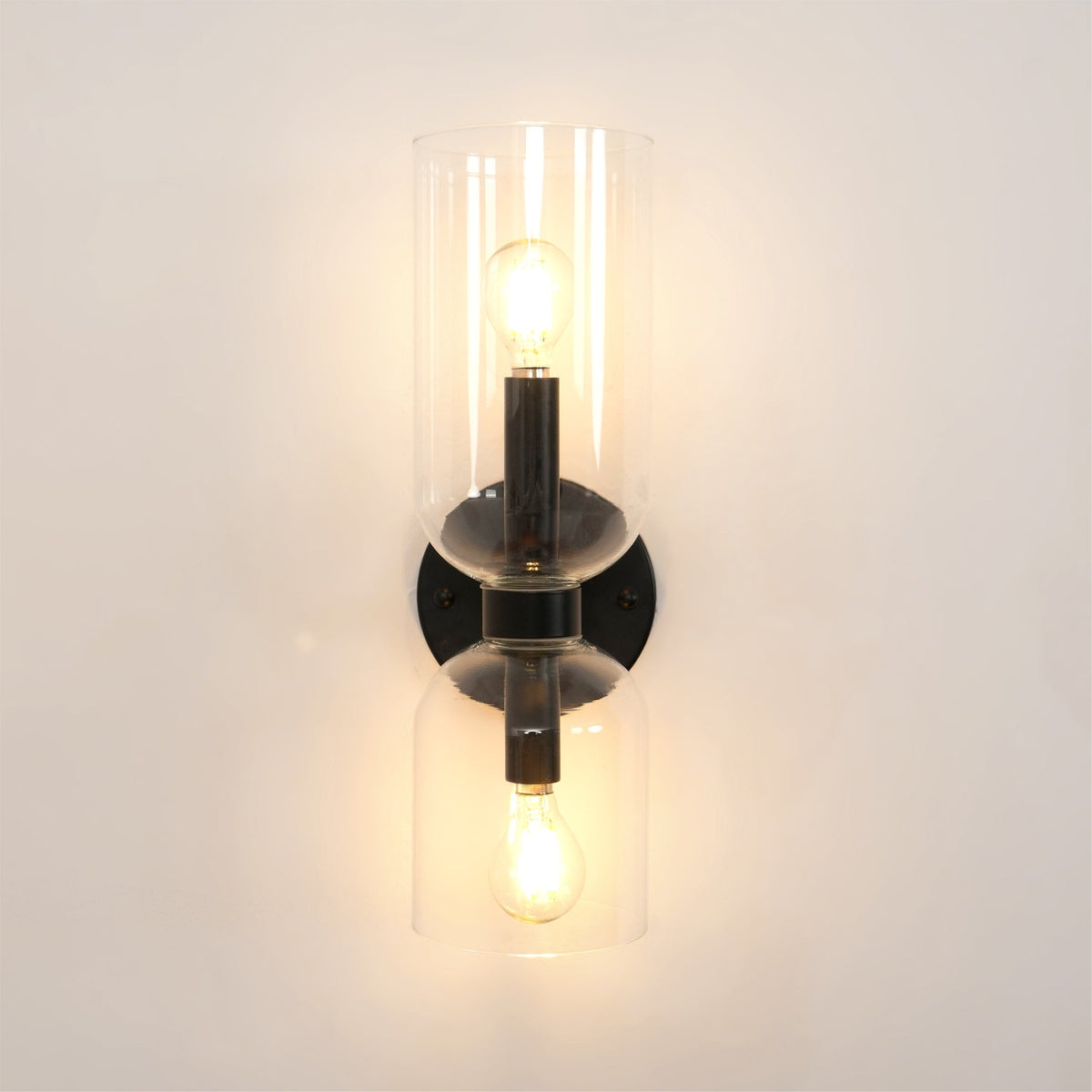 Front and centred, this matt black Clérachic sconce shows both bulbs lit through clear glass.