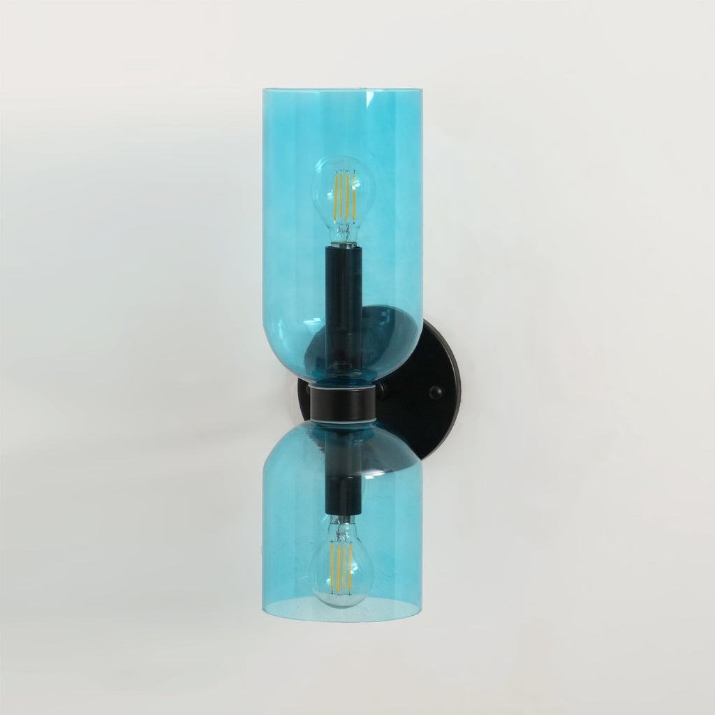 Blue glass cylinders glow softly on this matt black Clérachic wall light against white.