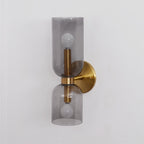 Angled against white, this gold Clérachic wall light's smoke grey shades glow around the bulbs.
