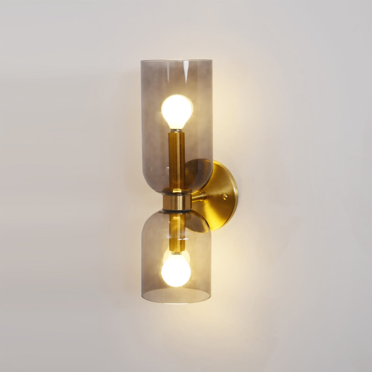 A front view of this gold Clérachic sconce shows smoke grey glass glowing over both bulbs.