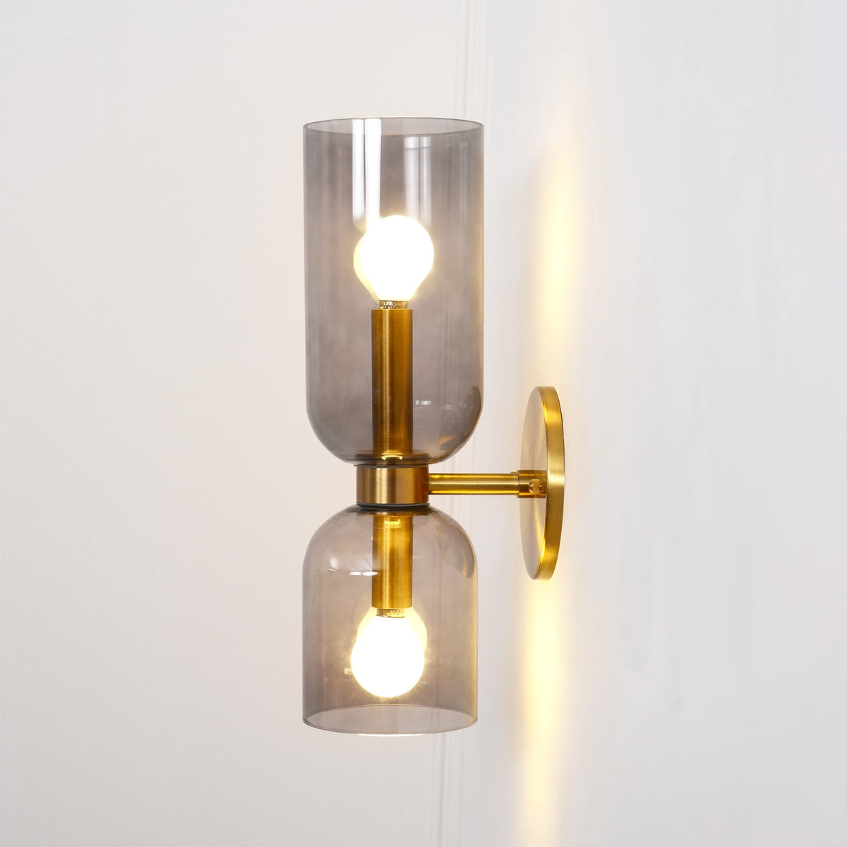 A faint wire trace runs beside this gold Clérachic sconce, its smoke grey shades lit.