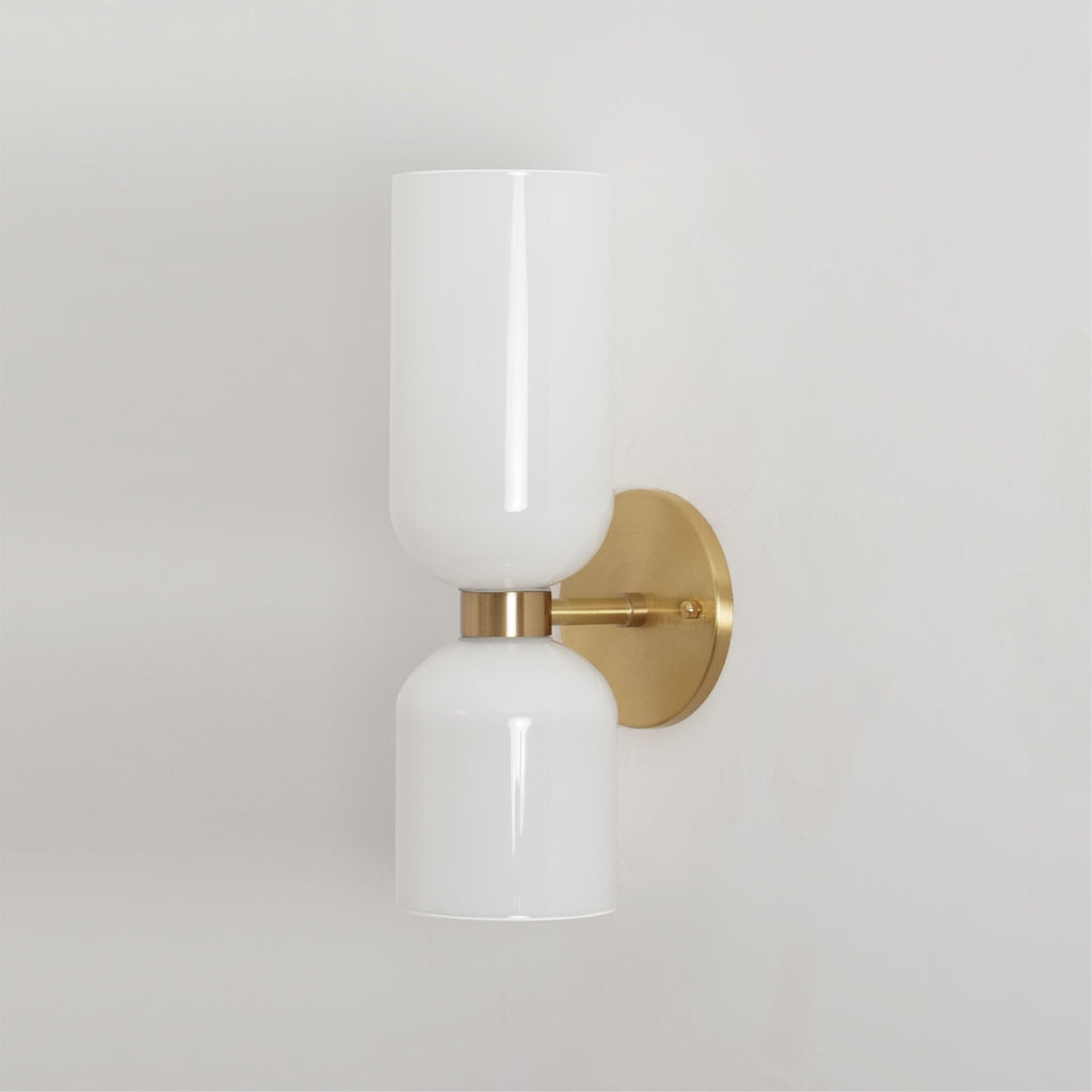 An angled view of this gold Clérachic wall light shows its glossy opal shades, unlit.