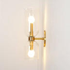Warm light spills onto the wall from this gold Clérachic wall light's clear glass shades.