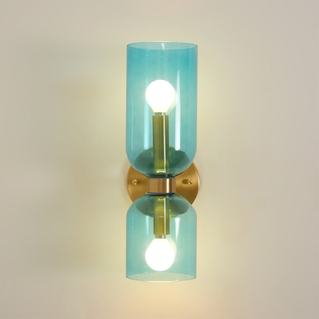 A close view of the blue glass cylinders on this gold Clérachic wall light, both bulbs lit.