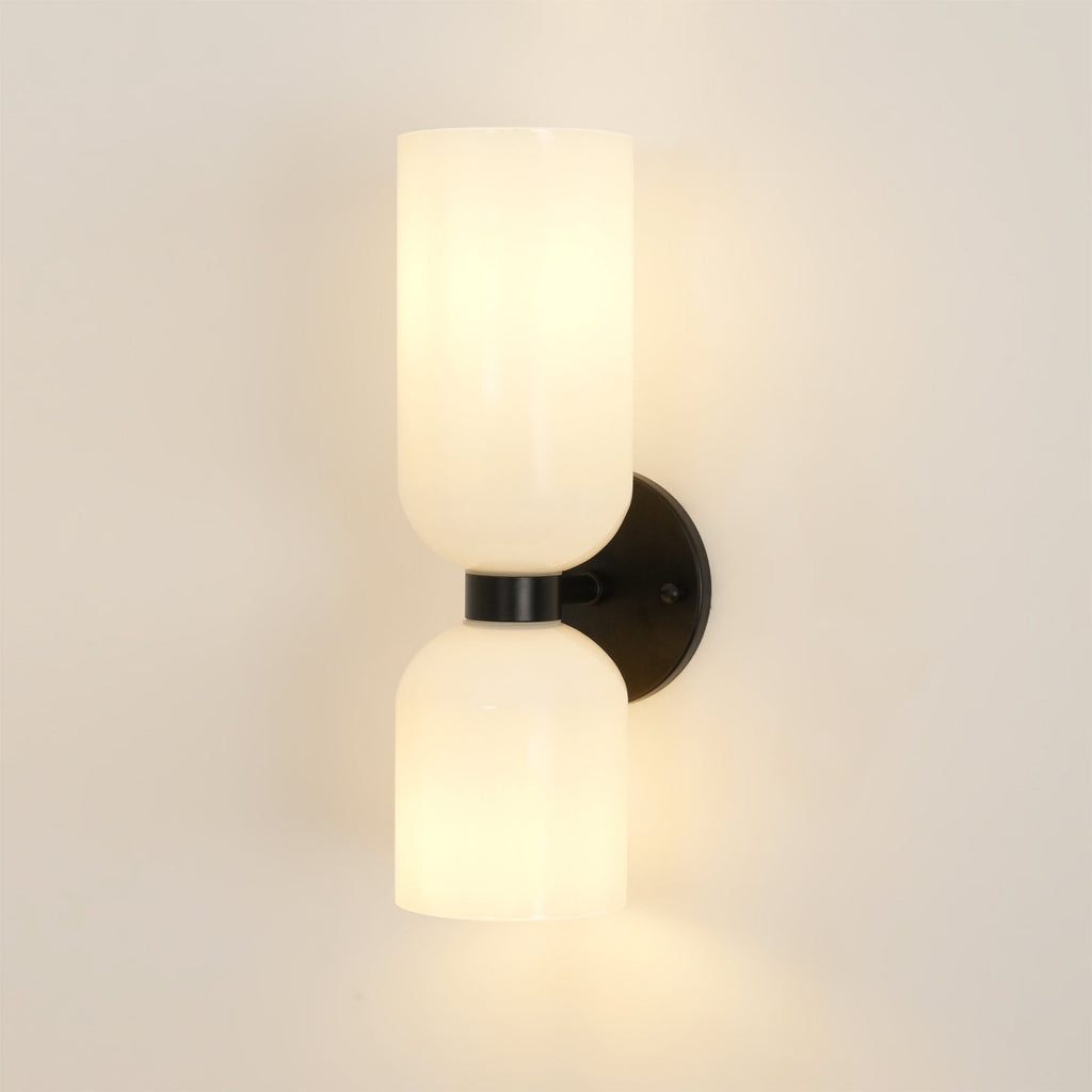 A front view of this Clérachic wall light in matt black, its opal shades unlit on a cream wall.