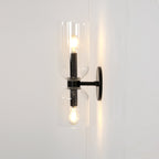 Set on a cream wall, this matt black Clérachic sconce's clear glass cylinders glow around each bulb.