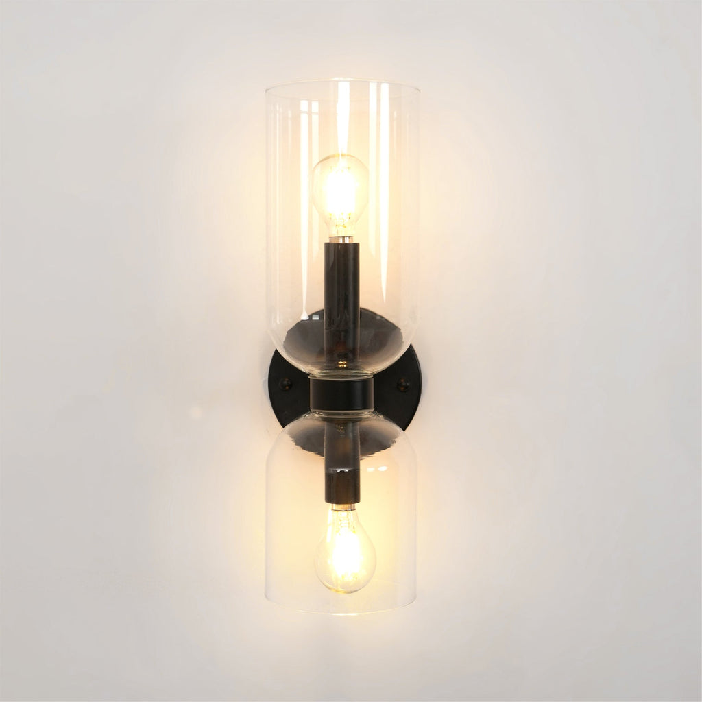 Centred on a white wall, this matt black Clérachic wall light's clear shades glow warmly.