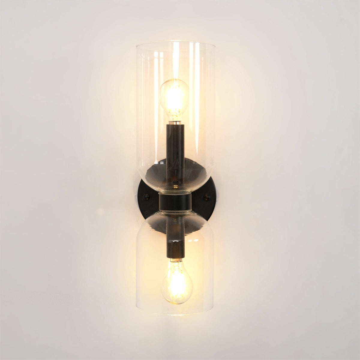 Centred on a white wall, this matt black Clérachic wall light's clear shades glow warmly.