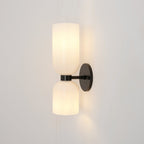 Unlit, the two opal glass shades of this matt black Clérachic sconce sit against a pale taupe wall.