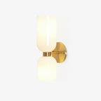 A side angle of this gold Clérachic sconce shows its two opal glass shades, unlit, on white.