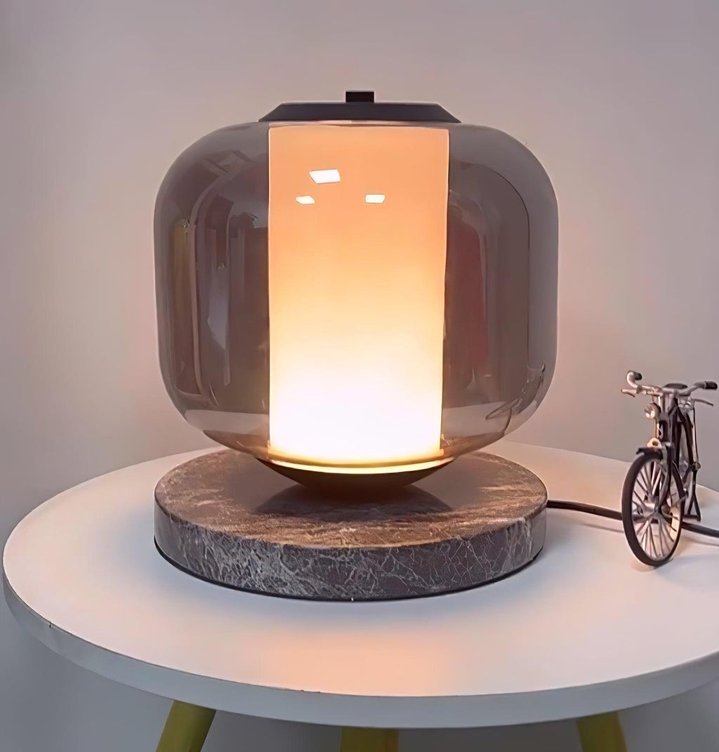 The Clérachic table lamp lit on its round table, shown from a slightly lower angle with the toy bicycle beside it.