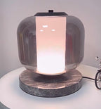 Tight crop on the Clérachic table lamp's glass shade, the warm light glowing softly through its frosted lower band.