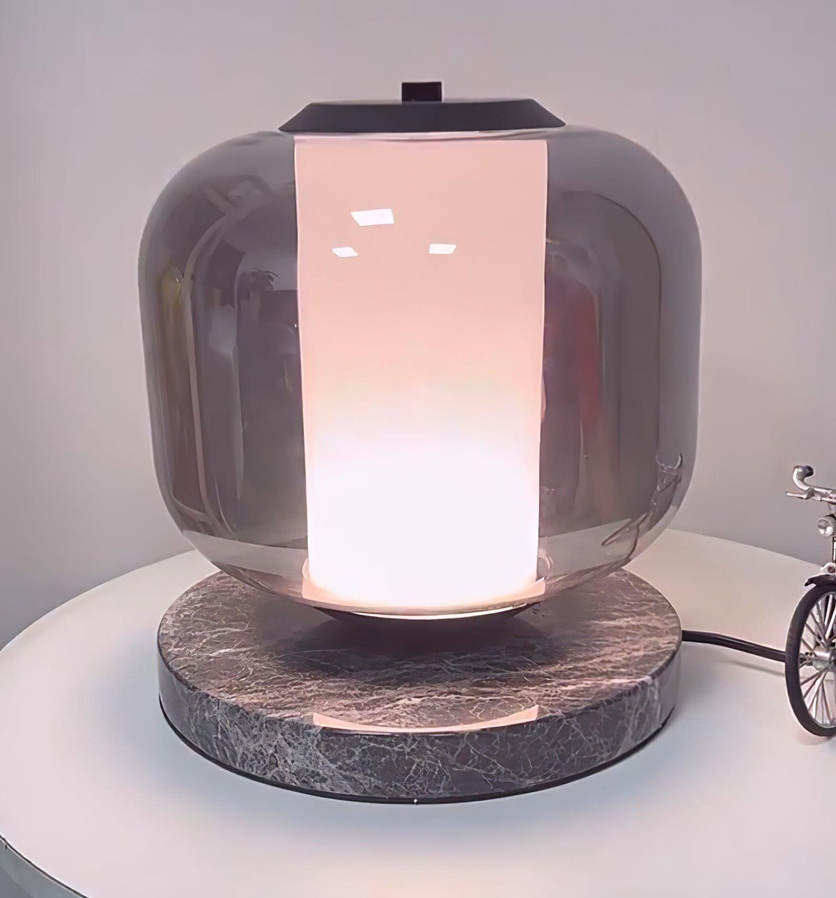 Tight crop on the Clérachic table lamp's glass shade, the warm light glowing softly through its frosted lower band.