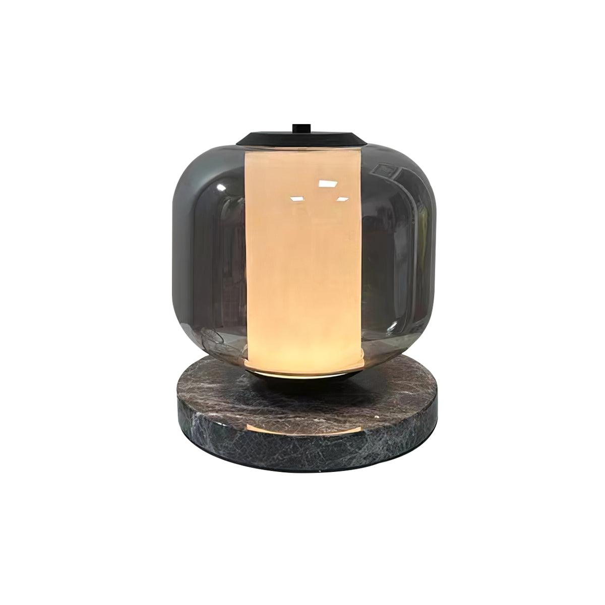A small full product shot of the Clérachic table lamp glowing warm amber, isolated against a plain grey background.