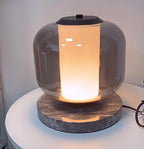Another close crop of the Clérachic table lamp's glass shade, the warm light glowing brighter through its lower half.