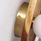 Walnut wood wall lamp shown lit against a neutral backdrop