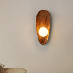 Walnut wood wall lamp shown at an angle showing depth