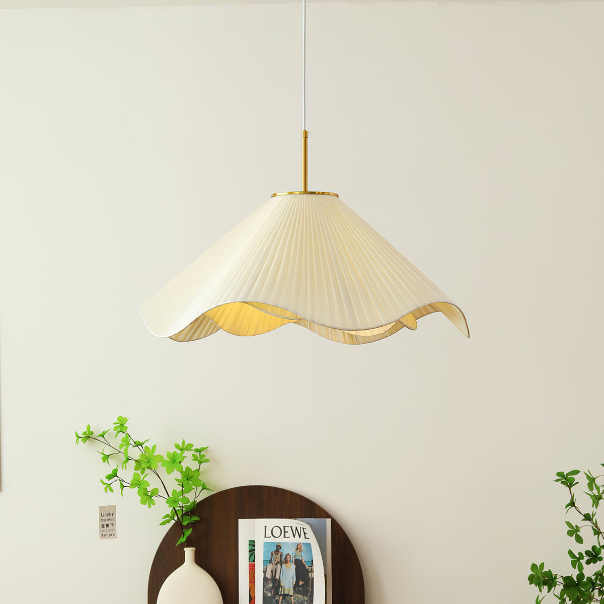 Above a dark wood console dressed with a vase and a magazine, this beige Clérachic pendant light glows softly.