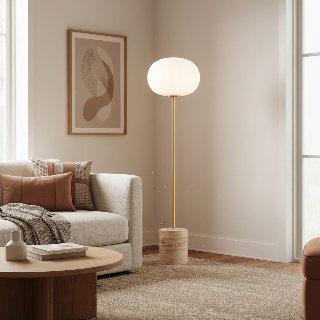 The Clérachic floor lamp lights a minimal corner beside a beige sofa with terracotta and rust-toned cushions.