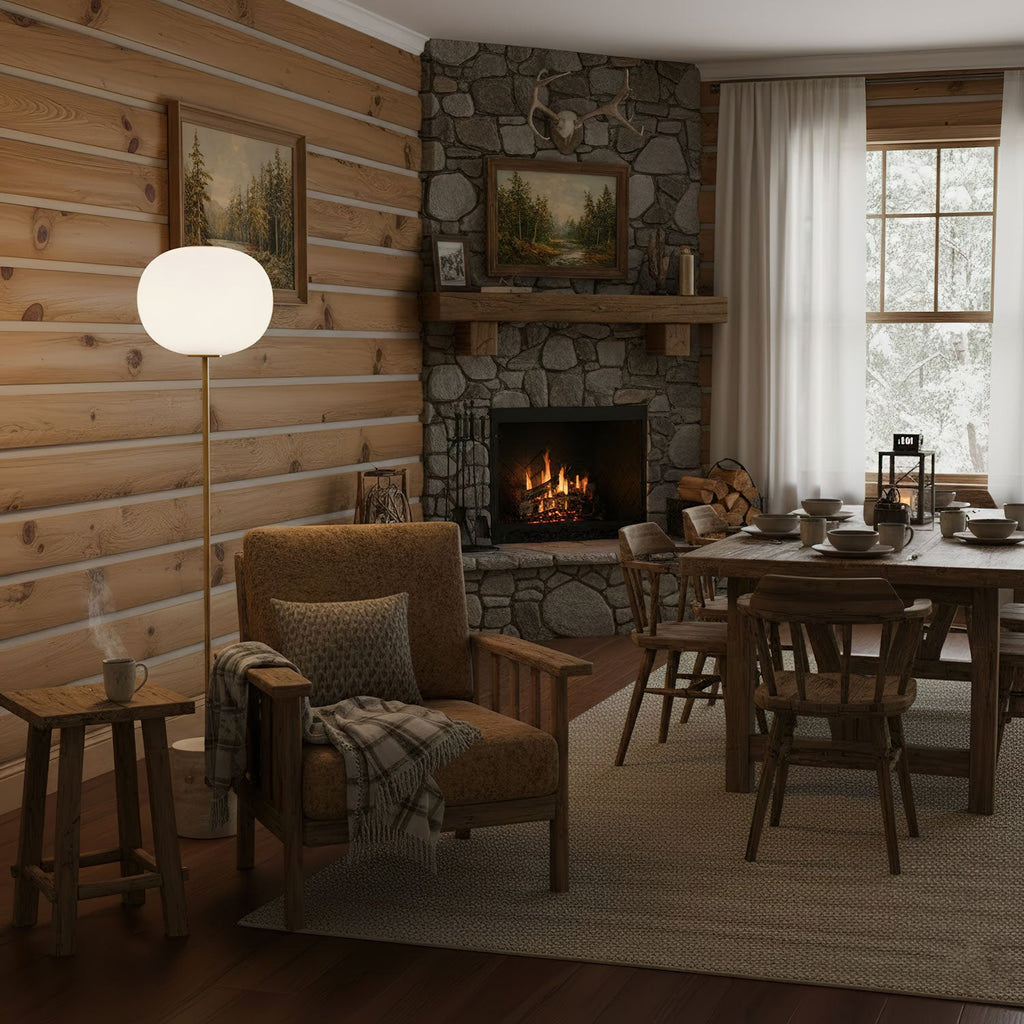 The Clérachic floor lamp lights a corner of a log cabin living space, with a wooden dining table set in the background.