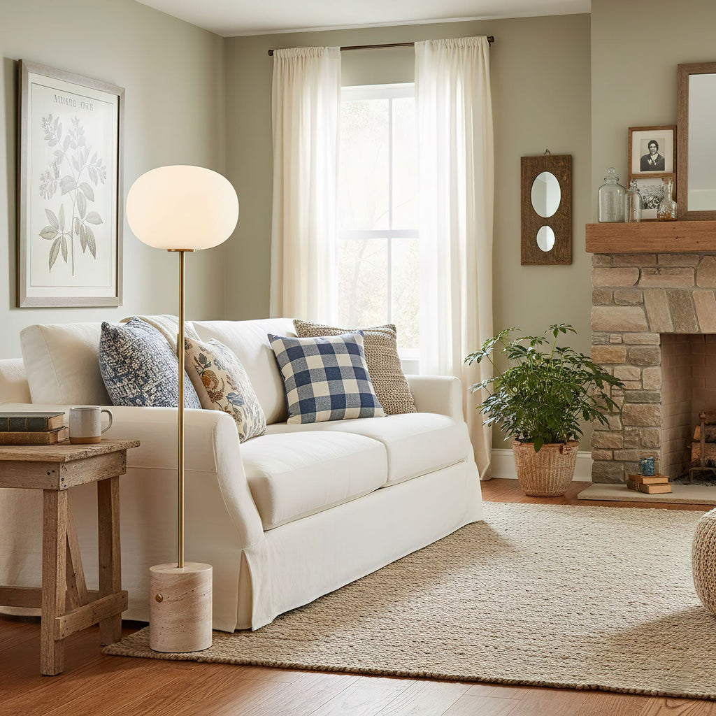 The Clérachic floor lamp stands beside a white slipcovered sofa with plaid pillows and a potted fern, in a sage-toned room.