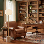 In a wood-panelled home office, the Clérachic floor lamp stands beside a brown leather armchair and built-in bookshelves.