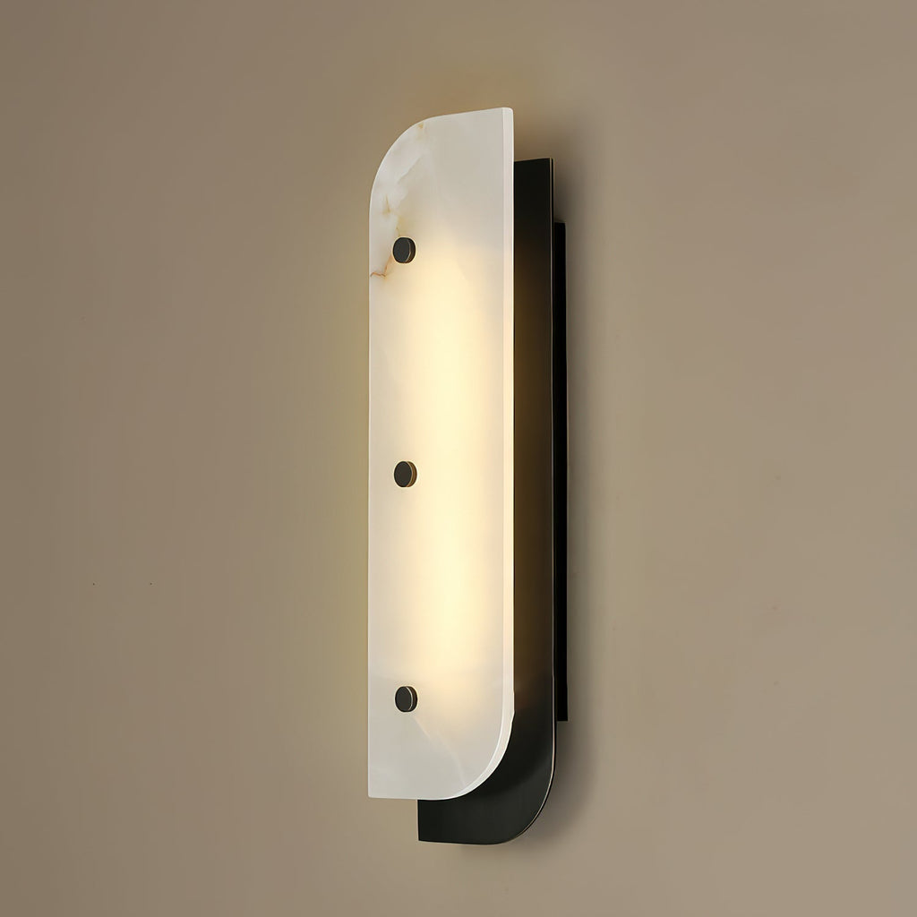 Tall Elaris Alabaster Wall Light in black on a taupe wall, the lit panel casting a soft halo above and below.