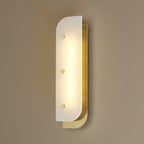 Tall Elaris Alabaster Wall Light in brass lit on a taupe wall, three studs spaced down the stone face.