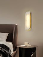 Tall Elaris Alabaster Wall Light in brass at the bedside, warm pool of light over the nightstand.