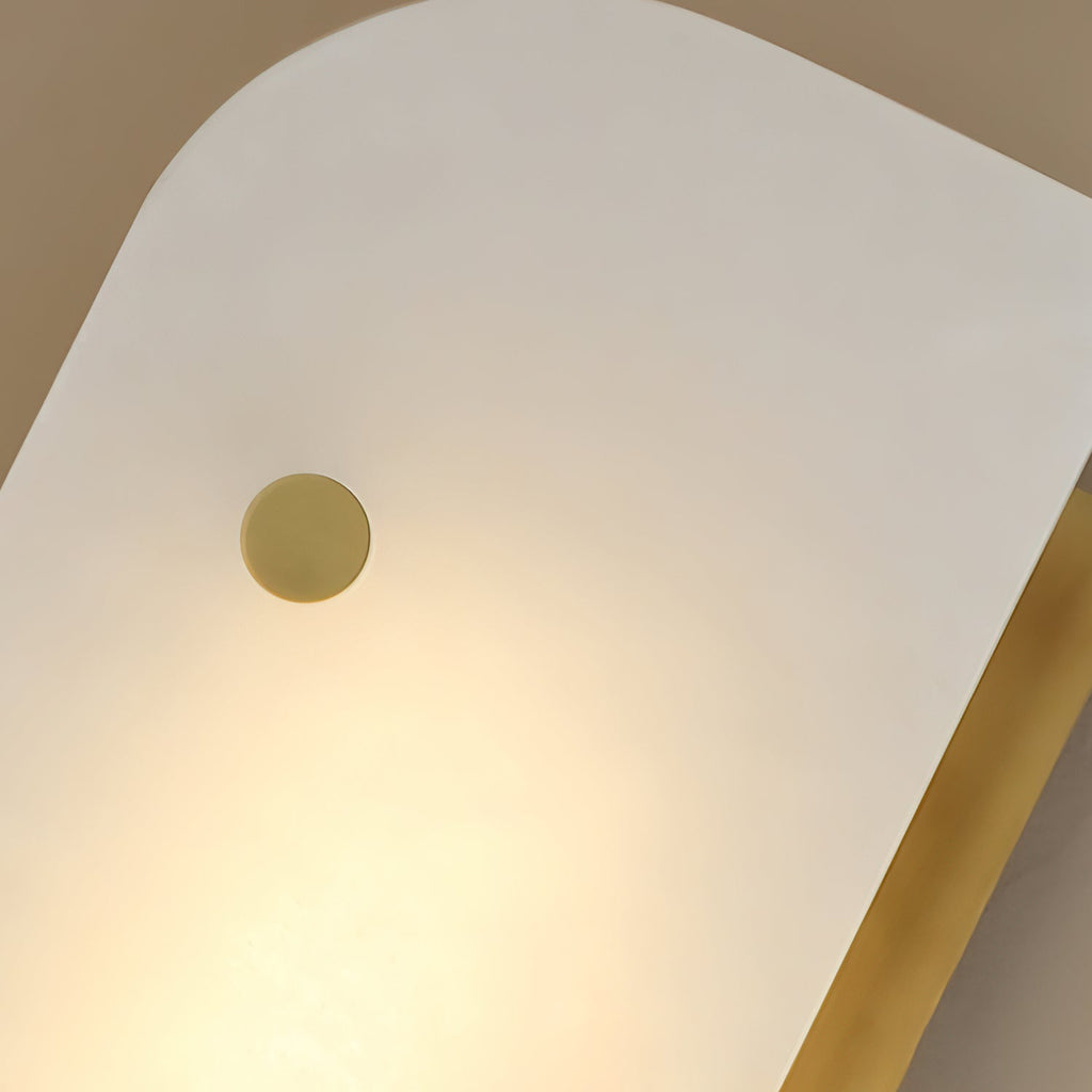 Macro of the Elaris wall light's alabaster panel and single brass stud, warm light glowing through the stone.
