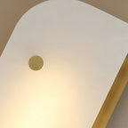 Macro of the Elaris wall light's alabaster panel and single brass stud, warm light glowing through the stone.