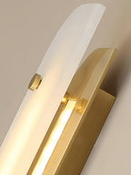 Angled close-up under the Elaris wall light, showing the LED strip tucked between stone panel and brass arm.