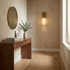 Beside an oval mirror and a walnut console, this brass Clérachic sconce lights a plastered entryway wall.