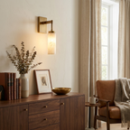 Beside a walnut console with books and a vase, this brass Clérachic sconce warms a living room corner.