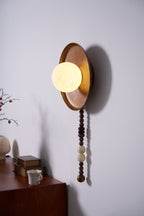 From another angle, the Clérachic sconce's shade projects forward above a dresser dressed with books and a vase.